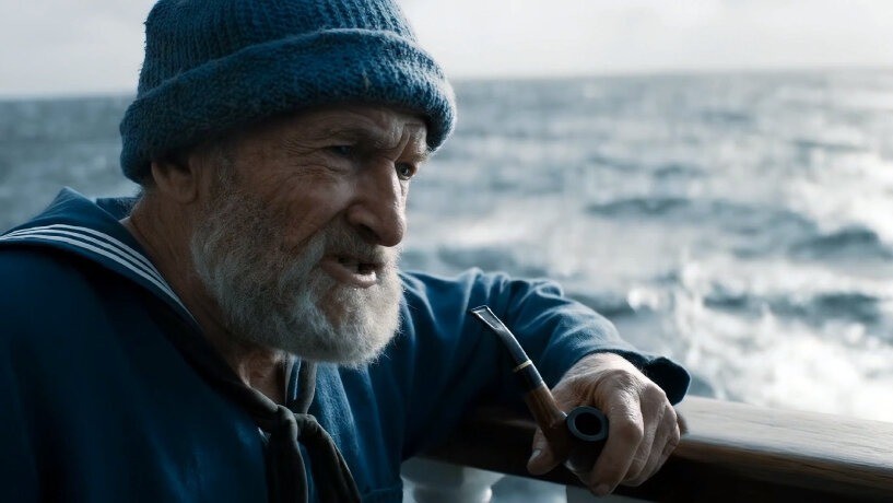 An older sailor holding a pipe at sea in a cinematic still