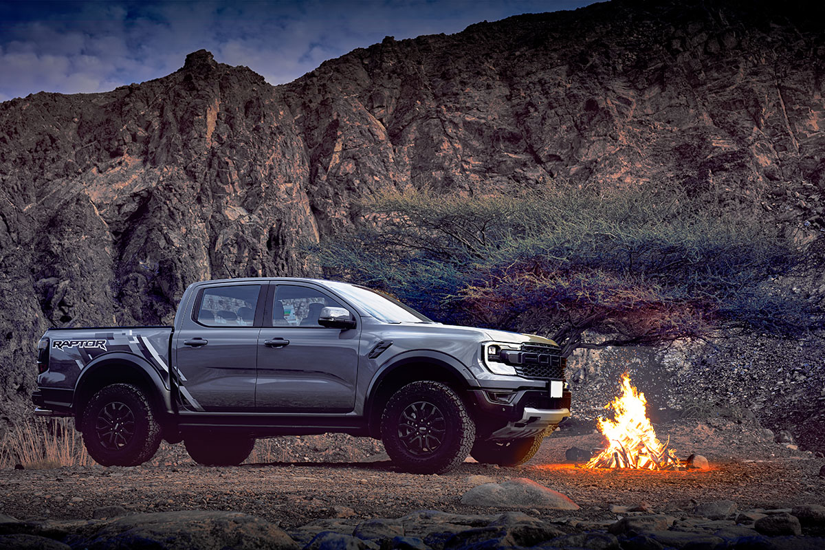 Ford Ranger Raptor parked beside a campfire in a rocky landscape