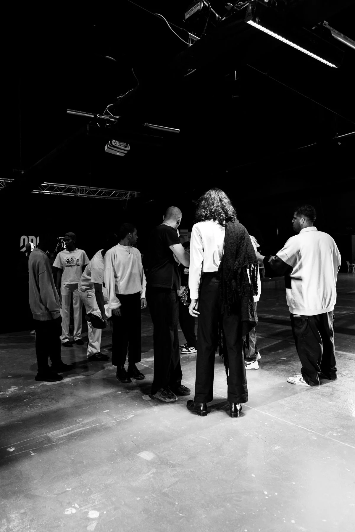 Backstage at a 2D2C2M fashion presentation, with models and crew under studio lights.