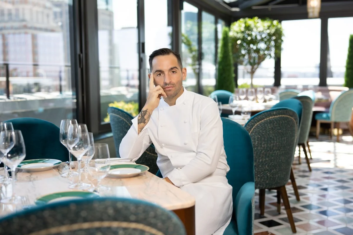 Chef Mario Carbone seated at a restaurant table.