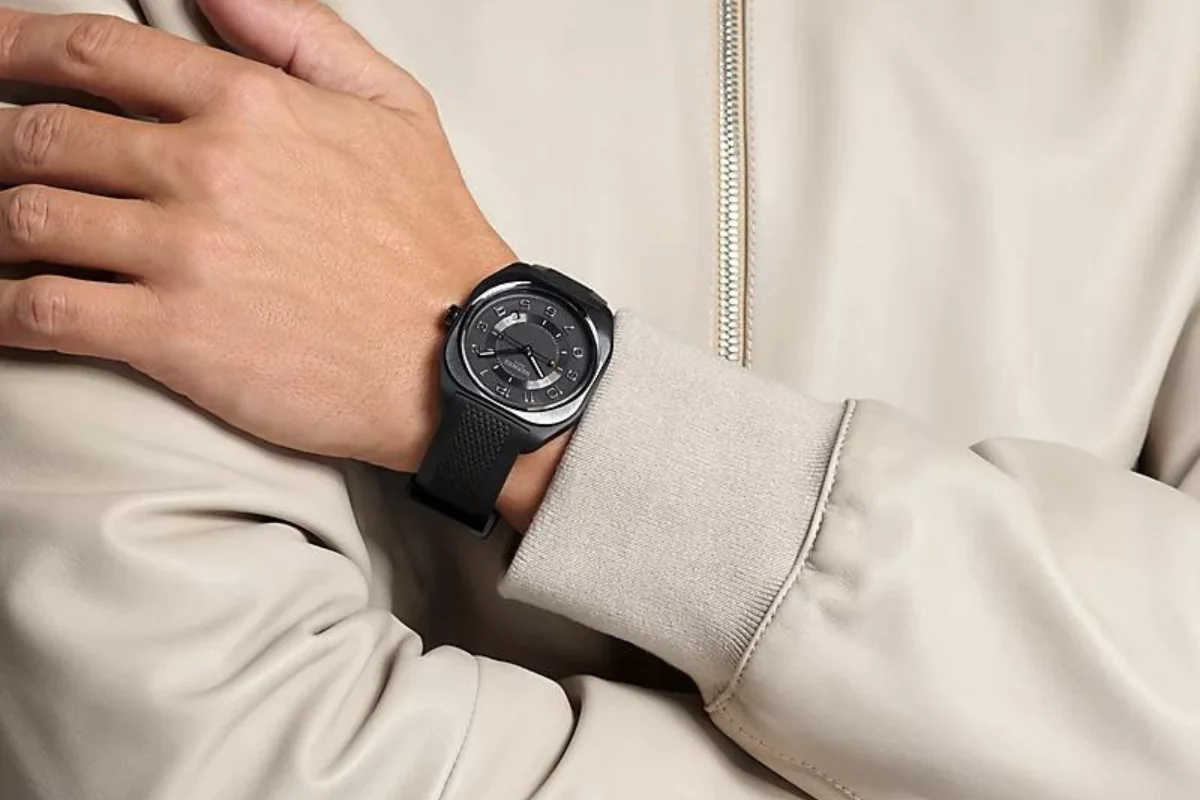 A black Hermès H08 watch worn with a cream jacket.
