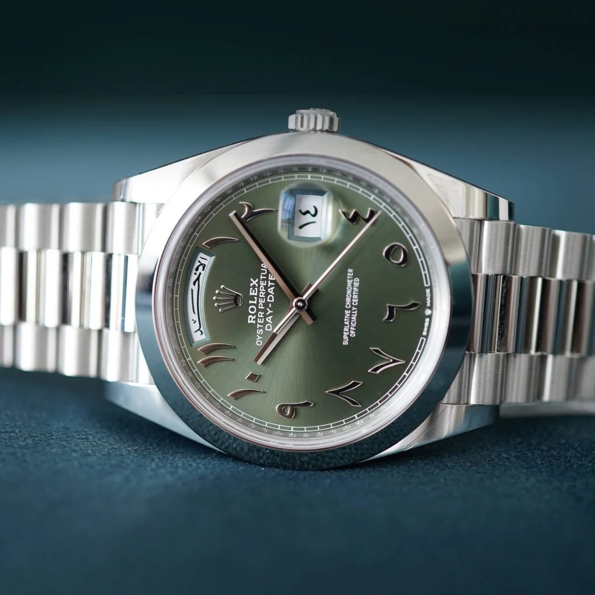 A Rolex Day-Date with Arabic numerals on a green dial.