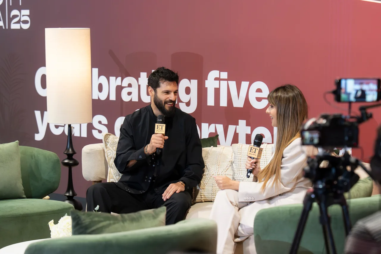 A festival press-junket interview with a camera recording the host and guest.
