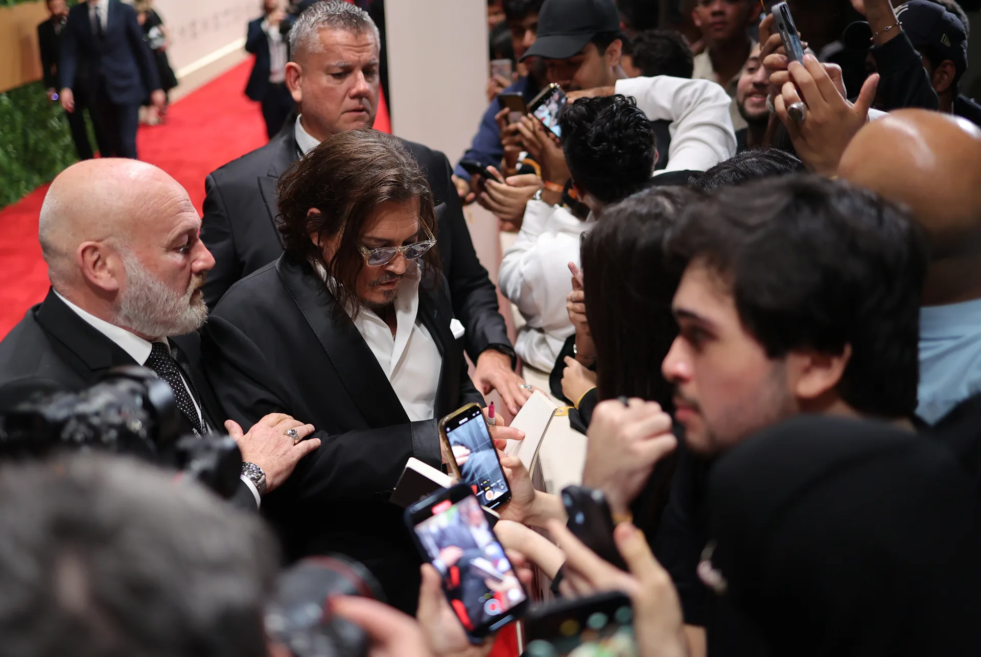 A guest signs autographs amid a crowd on the Festival red carpet.