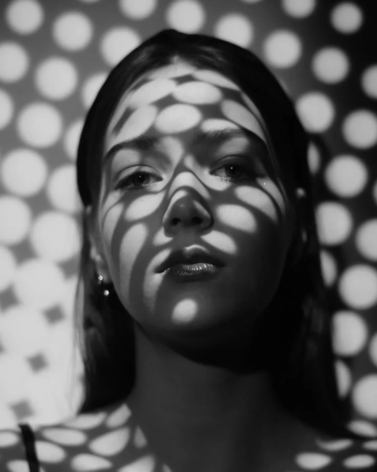 External art-direction reference showing geometric light projected across a portrait; not festival-produced evidence.