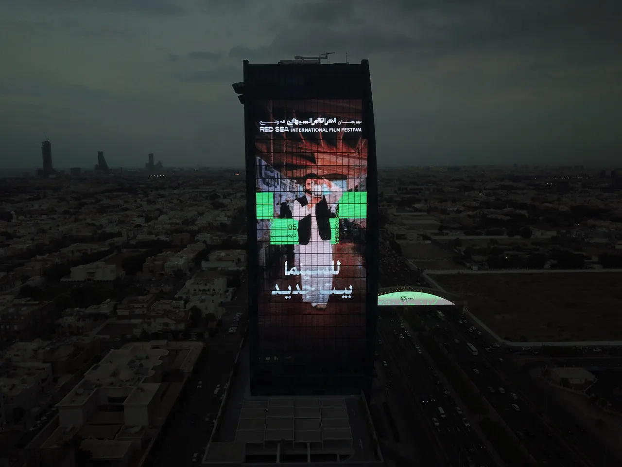 A Red Sea International Film Festival campaign fills a tower screen over a dark city skyline.